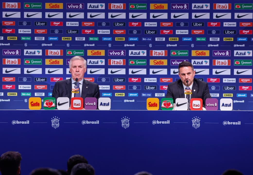 Coletiva de imprensa da convocação da seleção brasileira, 29OUT2026, com dois dirigentes e patrocinadores ao fundo.