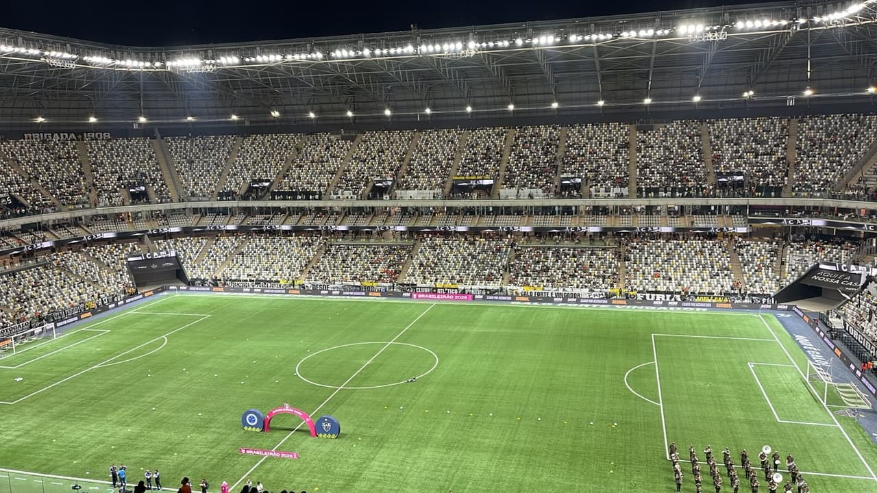 Arena MRV TR: estádio de futebol com arquibancadas cheias e gramado, arco rosa ao centro para cerimônia.