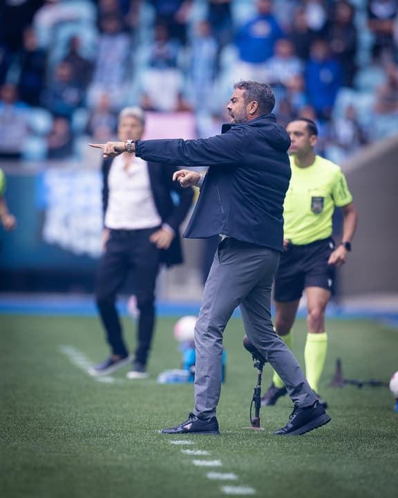 Artur Jorge aponta na Arena do Grêmio durante partida de futebol.