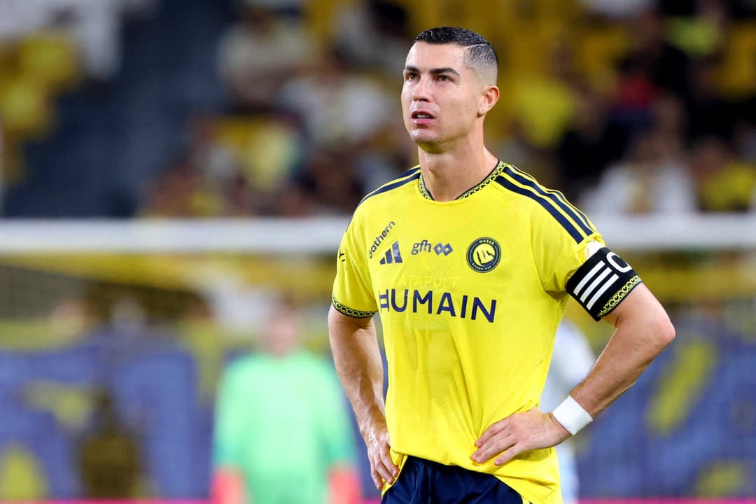 Jogador de futebol vestindo camisa amarela do Al Nassr, com braçadeira de capitão, em campo.