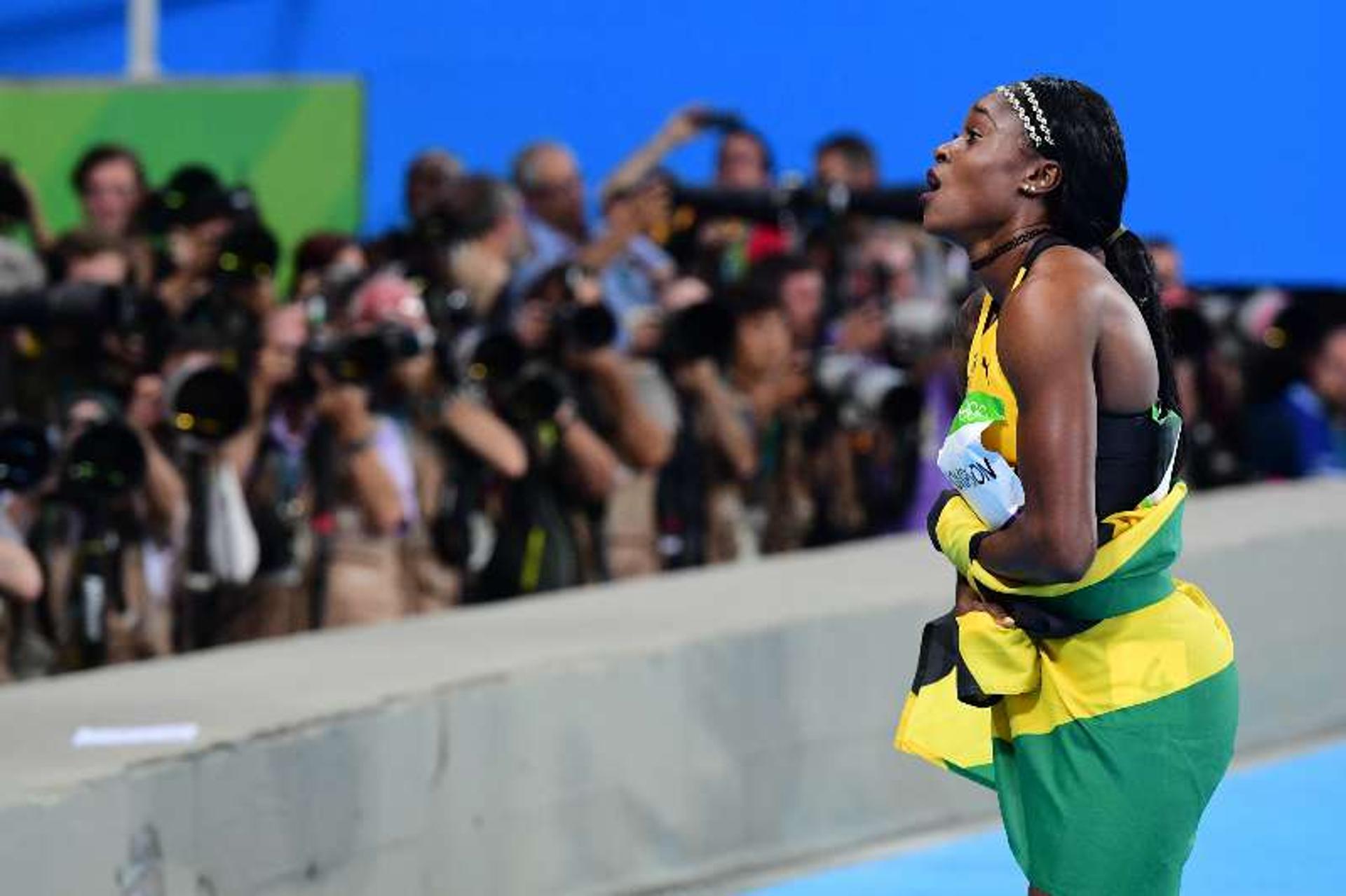 Elaine Thompson celebra com a bandeira da Jamaica após vitória nos 100m