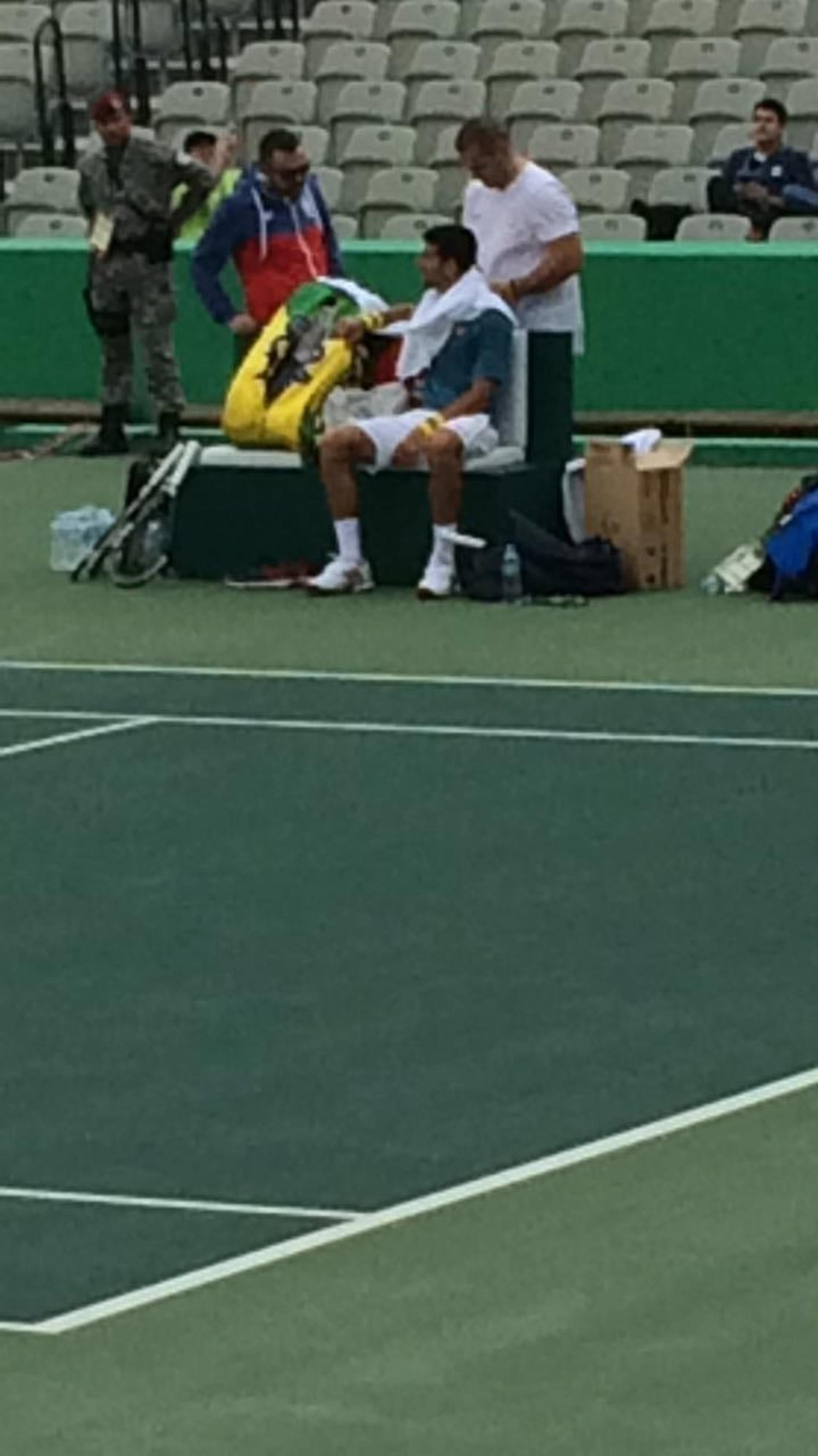 Stefan Duell massageia cotovelo de Novak Djokovic na quadra central do Centro Olímpico