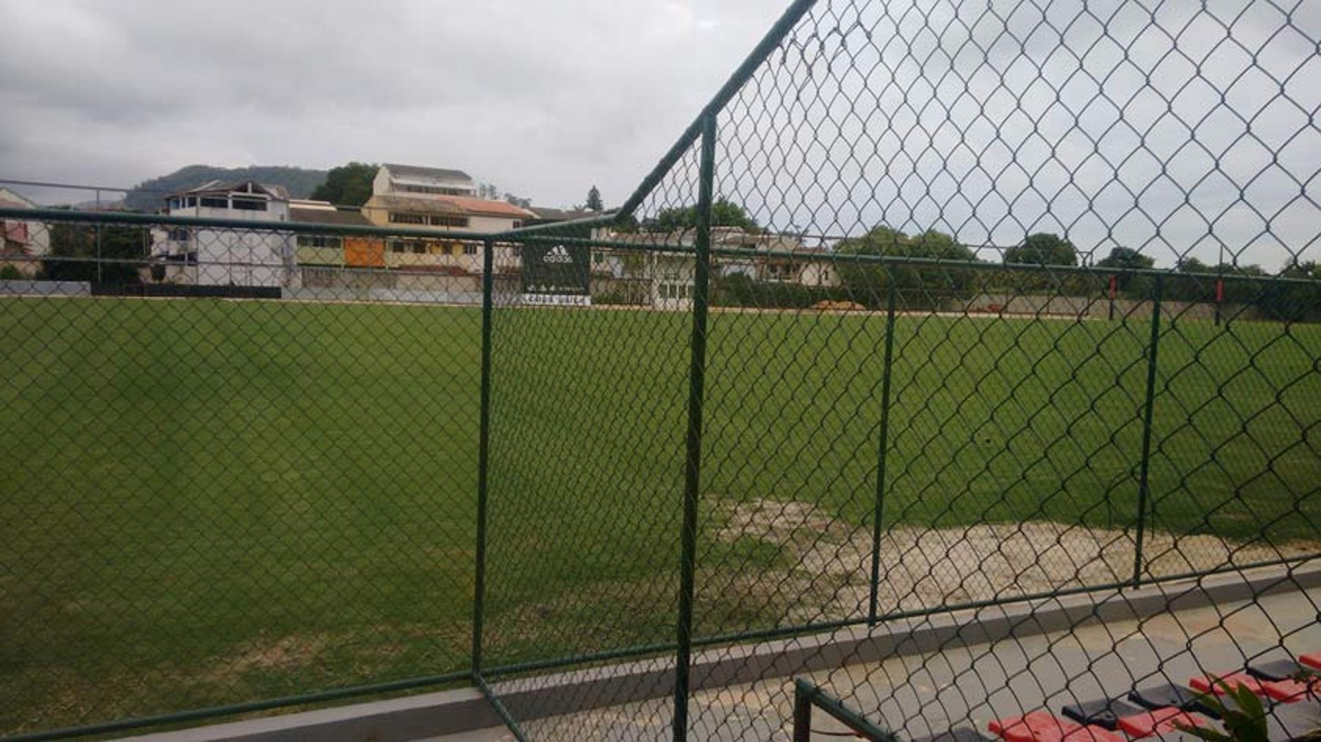 Campo 5 do Ninho do Urubu já tem gramado em com estado e marca de patrocinador de uniforme do Fla, ao fundo