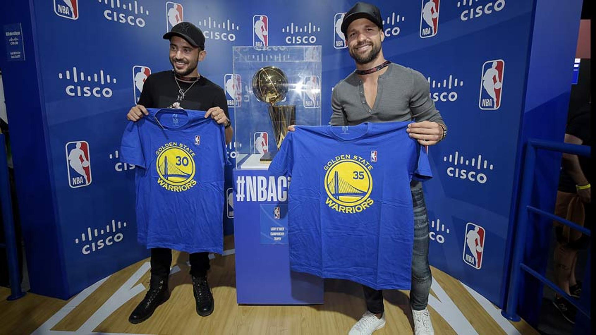 Éverton Ribeiro e Diego posam com camisas do GSW ao lado do troféu da NBA