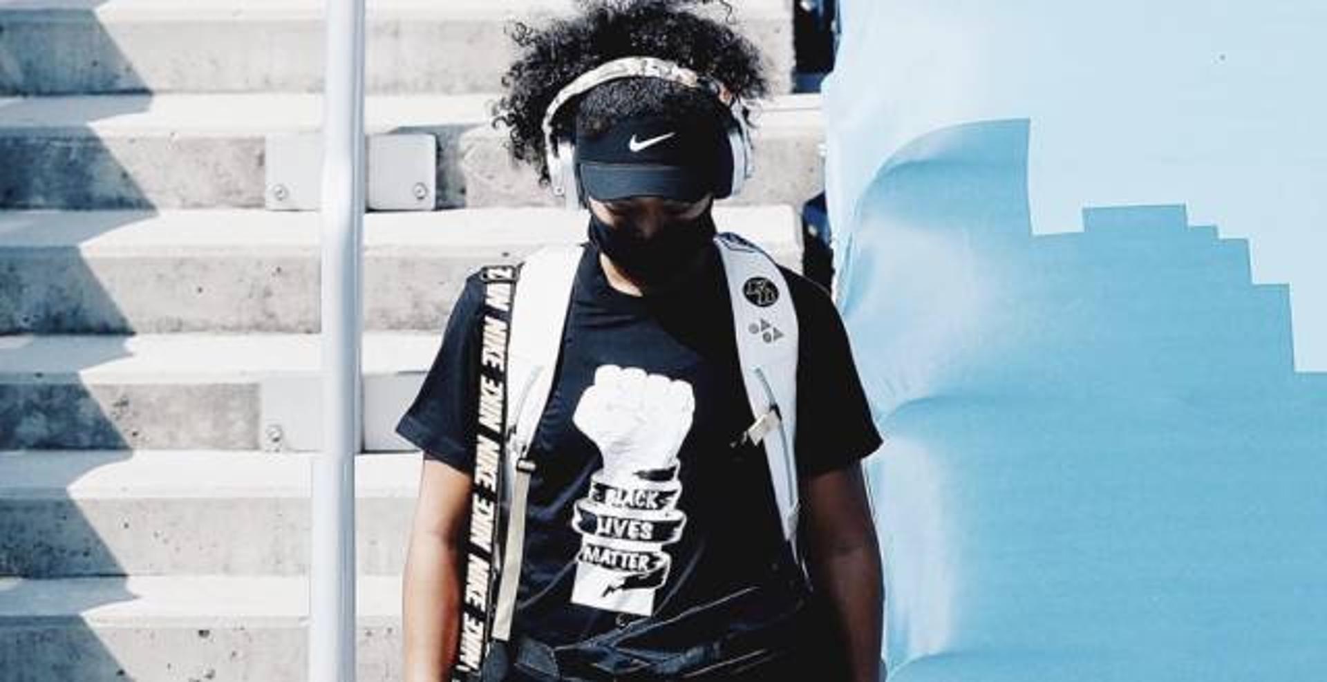 Naomi Osaka entrando em quadra no US Open, vestindo camiseta de processo