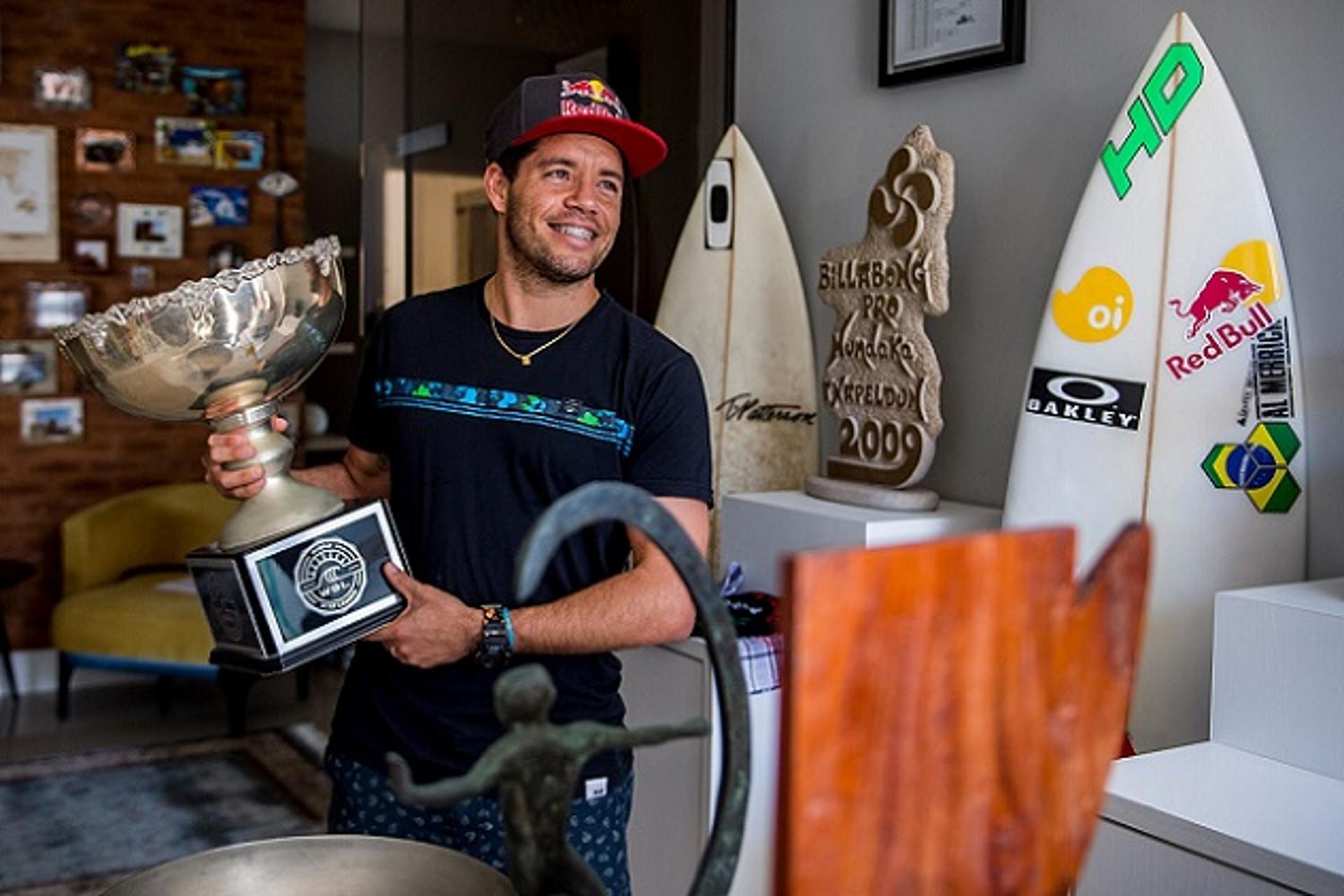 Adriano de Souza posa ao lado de troféus e pranchas marcantes na carreira (Crédito: Marcelo Maragni/Red Bull Content Pool)