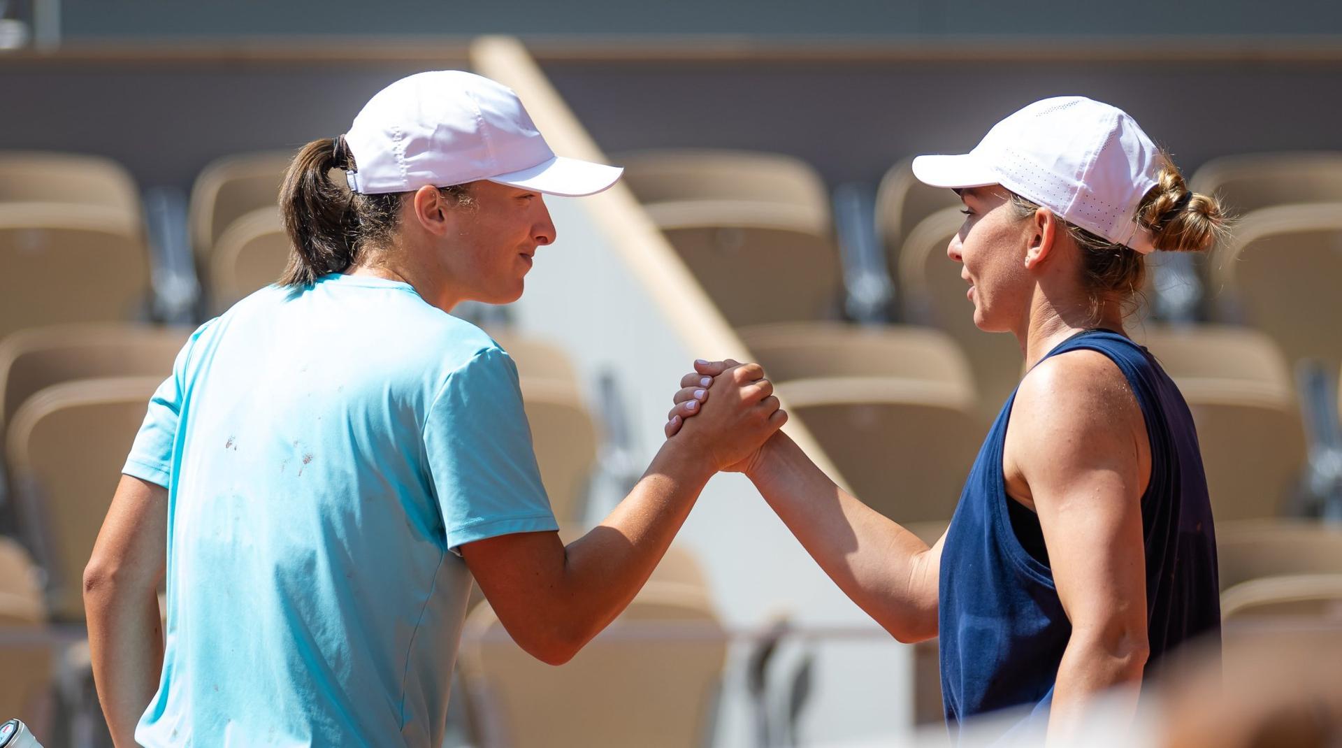 Iga Swiatek e Simona Halep se cumprimentam ao fim de treino em Paris