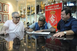 Jogador assina renovação ao lado do diretor de futebol Celso Chamun (E) e do vice de futebol Carlos Pellegrini (D) (Foto: Divulgação/Internacional)
