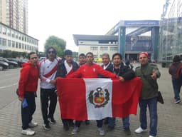 Torcedores do Peru posam com a bandeira na entrada do Estádio de Khimk antes do treino aberto da seleção
