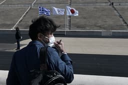 Homem de máscara na cerimônia com a tocha olímpica na Grécia (AFP)