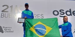 Jonathan Cruz, com a placa em homenagem a Luiz Antônio dos Santos dada pela Meia Maratona de Buenos Aires, e a treinadora Adriana Aparecida da Silva. (Divulgação)