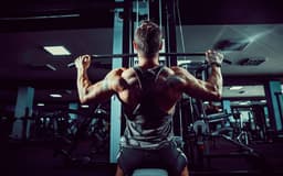bodybuilder-forte-que-faz-o-exercicio-pesado-para-tras-na-maquina-scaled-aspect-ratio-512-320