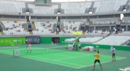 Tenistas em partida de duplas na arena olímpica.