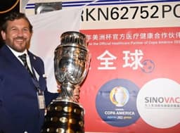 Alejandro Domínguez posa com taça da Copa América ao lado de lote das vacinas