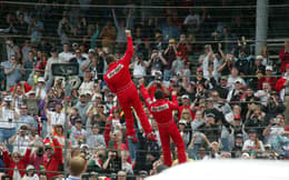Gil-de-Ferran-and-Helio-Castroneves-climb-the-fence-after-the-2003-Indianapolis-500_Large-Image-Without-Watermark_m95743-scaled-aspect-ratio-512-320