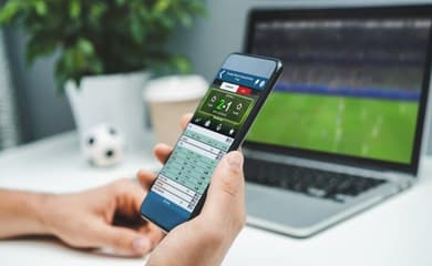 Uma bola de futebol e um smartphone um aplicativo de apostas para anunciar  jogos de futebol e casa de apostas