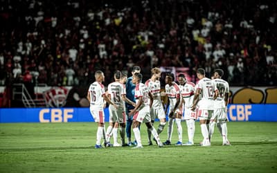 Jogadores do Flamengo com a camisa branca se reúnem no meio do gramado