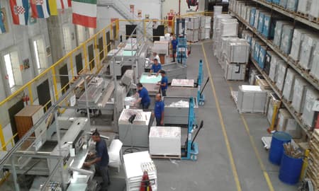 GALERIA: A fábrica da Panini em imagens. Na foto, homens trabalham nas guilhotinas que cortam as figurinhas em blocos