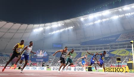 Christian Coleman (dir.) cruza a linha de chegada e vence os 100 m do Mundial de atletismo, diante de arquibancadas vazias (Crédito: Jewel Samad/AFP)