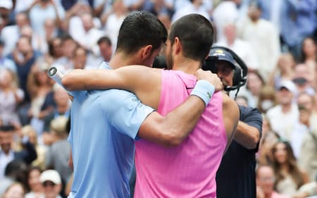 O espanhol Carlos Alcaraz (d) é abraçado pelo sérvio Novak Djokovic após a semifinal do US Open (Foto: TIMOTHY A. CLARY / AFP)