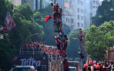 Torcedores do Flamengo sobem em postes para acompanhar o trio com os jogadores na festa de comemoração da Libertadores (Foto: PORCIUNCULA / AFP)