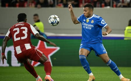 Mbappé conduz a bola e é marcado por Rodinei em Olympiacos x Real Madrid pela Champions League (Foto: Angelos Tzortzinis / AFP)