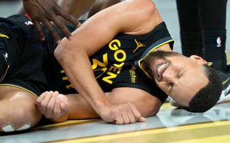 Stephen Curry deitado com dores em jogo entre Warriors e Rockets na NBA (Foto: Thearon W. Henderson/Getty Images/AFP)