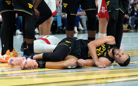 Stephen Curry deitado com dores em jogo entre Warriors e Rockets na NBA (Foto: Thearon W. Henderson/Getty Images/AFP)