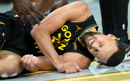 Stephen Curry deitado com dores em jogo entre Warriors e Rockets na NBA (Foto: Thearon W. Henderson/Getty Images/AFP)