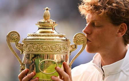 O italiano Jannik Sinner beija seu quarto Grand Slam, o primeiro em Wimbledon (Foto: Kirill KUDRYAVTSEV / AFP)