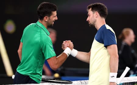 Novak Djokovic cumprimenta Pedro Martínez após a partida do Australian Open, em Melbourne, em 19 de janeiro de 2026. (Foto: David Gray/AFP)