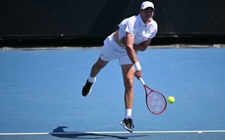 João Fonseca saca na estreia do Australian Open contra o americano Eliot Spizzirri (Foto: WILLIAM WEST / AFP)