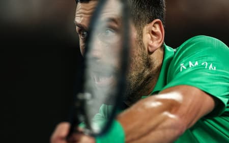 O sérvio Novak Djokovic devolve a bola na partida contra o italiano Jannik Sinner na semifinal do Australian Open (Foto: IZHAR KHAN / AFP)
