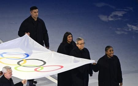 Rebeca Andrade carregando a bandeira olímpica na abertura do Jogos de Milão-Cortina (Foto: Piero CRUCIATTI / AFP)