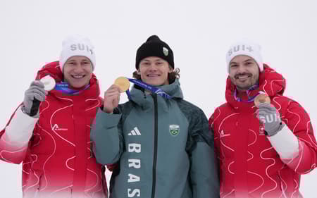 Da esquerda para a direita, Marco Odermatt (prata), Lucas Pinheiro Braathen (ouro) e Loic Meillard (bronze) celebram no pódio do slalom gigante masculino em 2026. (Foto: Dimitar Dilkoff/AFP)