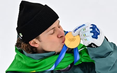 Lucas Pinheiro Braathen beija a medalha de ouro no pódio do slalom gigante masculino em 2026. (Foto: Fabrice Coffrini/AFP)