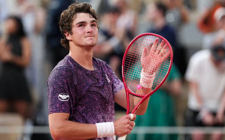 O brasileiro João Fonseca comemora após vencer o sérvio Novak Djokovic ao final da partida de simples masculina no sexto dia do torneio de tênis de Roland Garros, na quadra Philippe-Chatrier, em Paris (Foto: Dimitar Dilkoff / Afp)