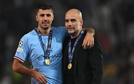 O meio-campista Rodri ao lado do treinador Pep Guardiola (Foto: Paul Ellis/AFP)