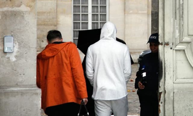 Benzema, de casaco branco, presta depoimento (Foto: Matthieu Alexandre / AFP)