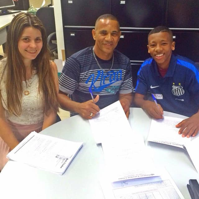 Nicolas assinando contrato ao lado do pai e de Marisa Alija Ramos