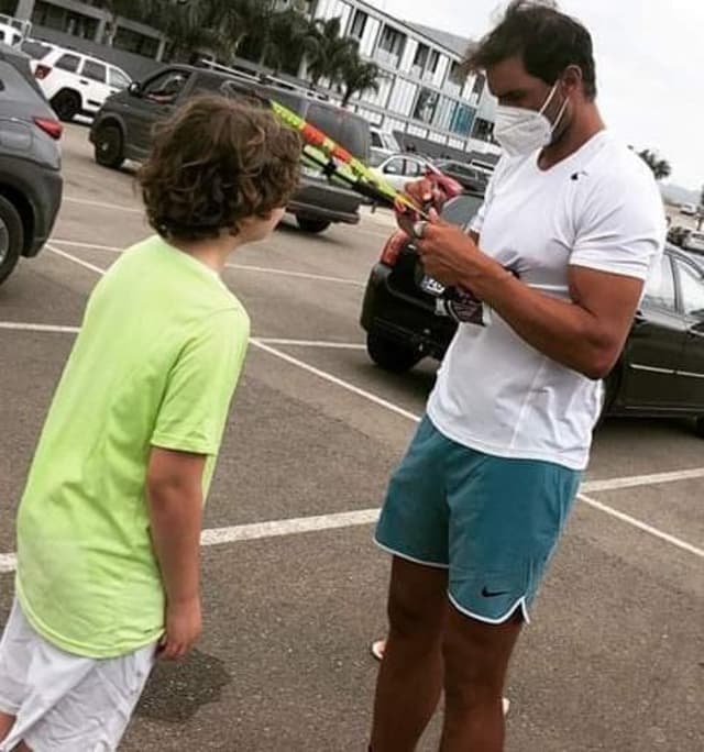 De máscara, Rafael Nadal dá autógrafo a pequeno fã