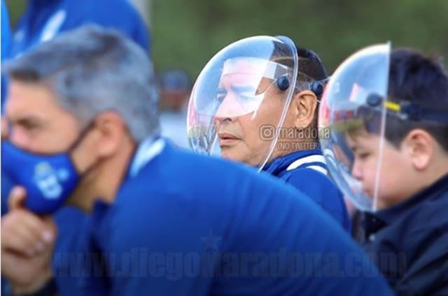 Maradona e seu filho usando proteção de acrílico em amistoso do Gimnasia