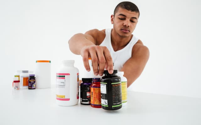 sportsman-standing-white-wall-holding-vitamins-scaled-aspect-ratio-512-320