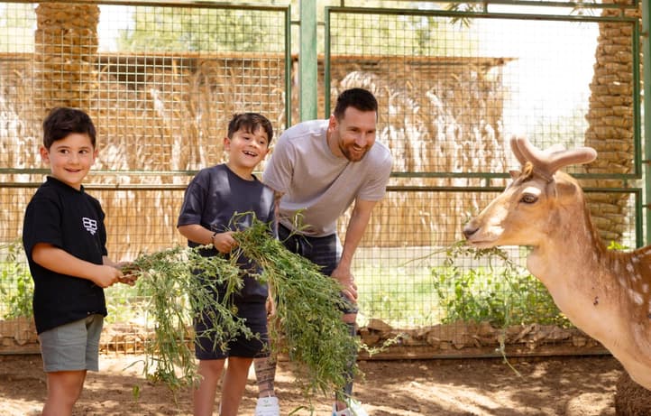 Lionel Messi e os filhos alimentando uma gazela (Foto: Divulgação / Ministério do Turismo Saudita)