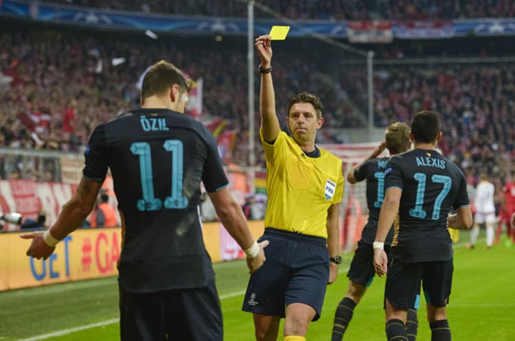 Özil recebe amarelo após fazer gol de mão (Foto: Guenter Schiffmann / AFP)