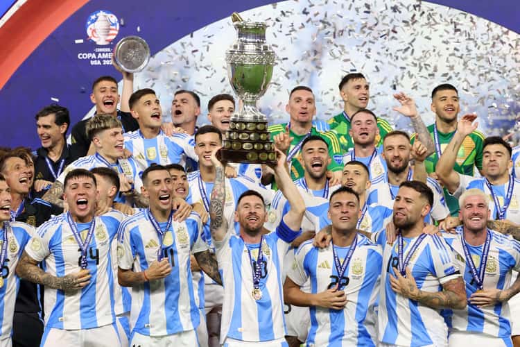 Messi ergue o troféu de campeão da Copa América de 2024, e jogadores da Argentina celebram o título