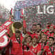 O fim de semana consagrou o Benfica como campeão português. O zagueiro e capitão Luisão ergue a taça