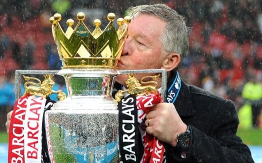 Sir Alex Ferguson dá um beijo na taça da Premier League conquistada pelo Manchester United em 2013, seu último título