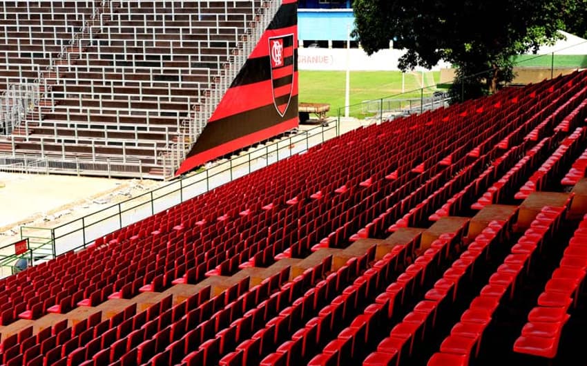 Cadeiras em vermelho na tribuna e setor Sul (espaço dos visitantes), ao fundo, com símbolo do Flamengo