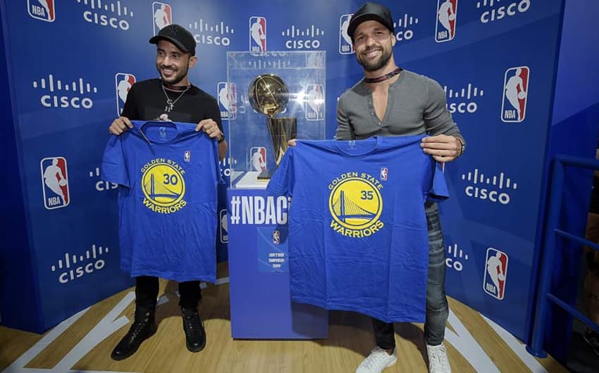 Éverton Ribeiro e Diego posam com camisas do GSW ao lado do troféu da NBA